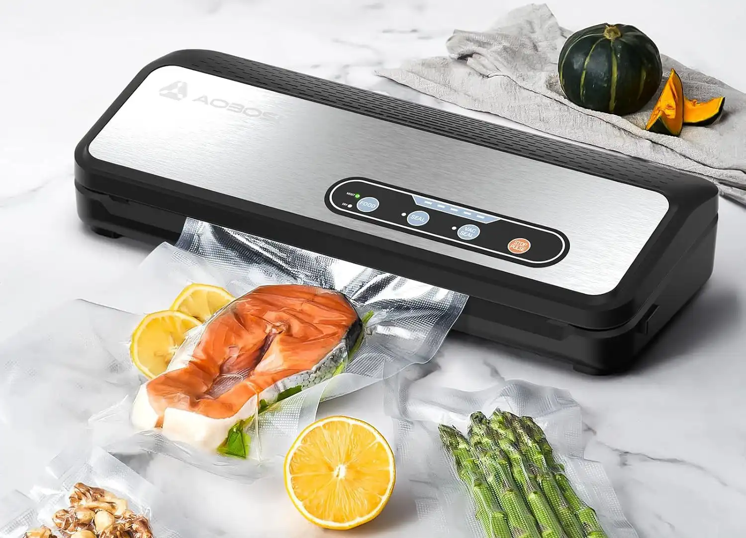 Selladora al vacío de alimentos con filete de salmón, espárragos y rodajas de limón en bolsas selladas al vacío.