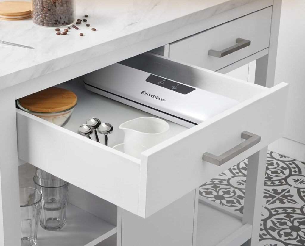 marinador envasadora la vacio foodsaver guardada en un cajón de cocina blanca moderna con utensilios y frascos.